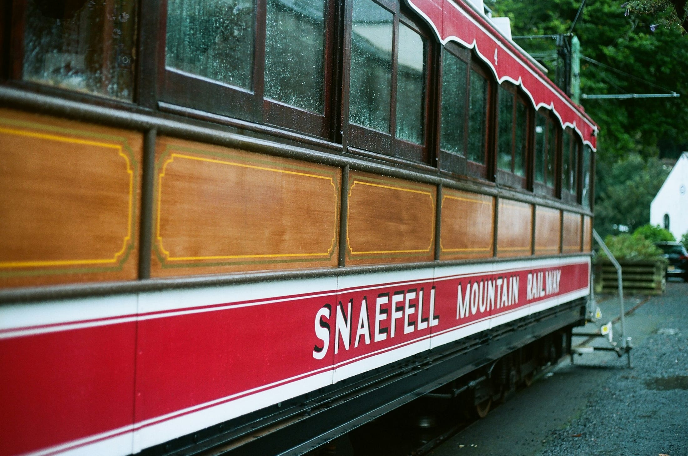 A red and cream Snaefell Mountain Railway tram car at Laxey, wet from the rain