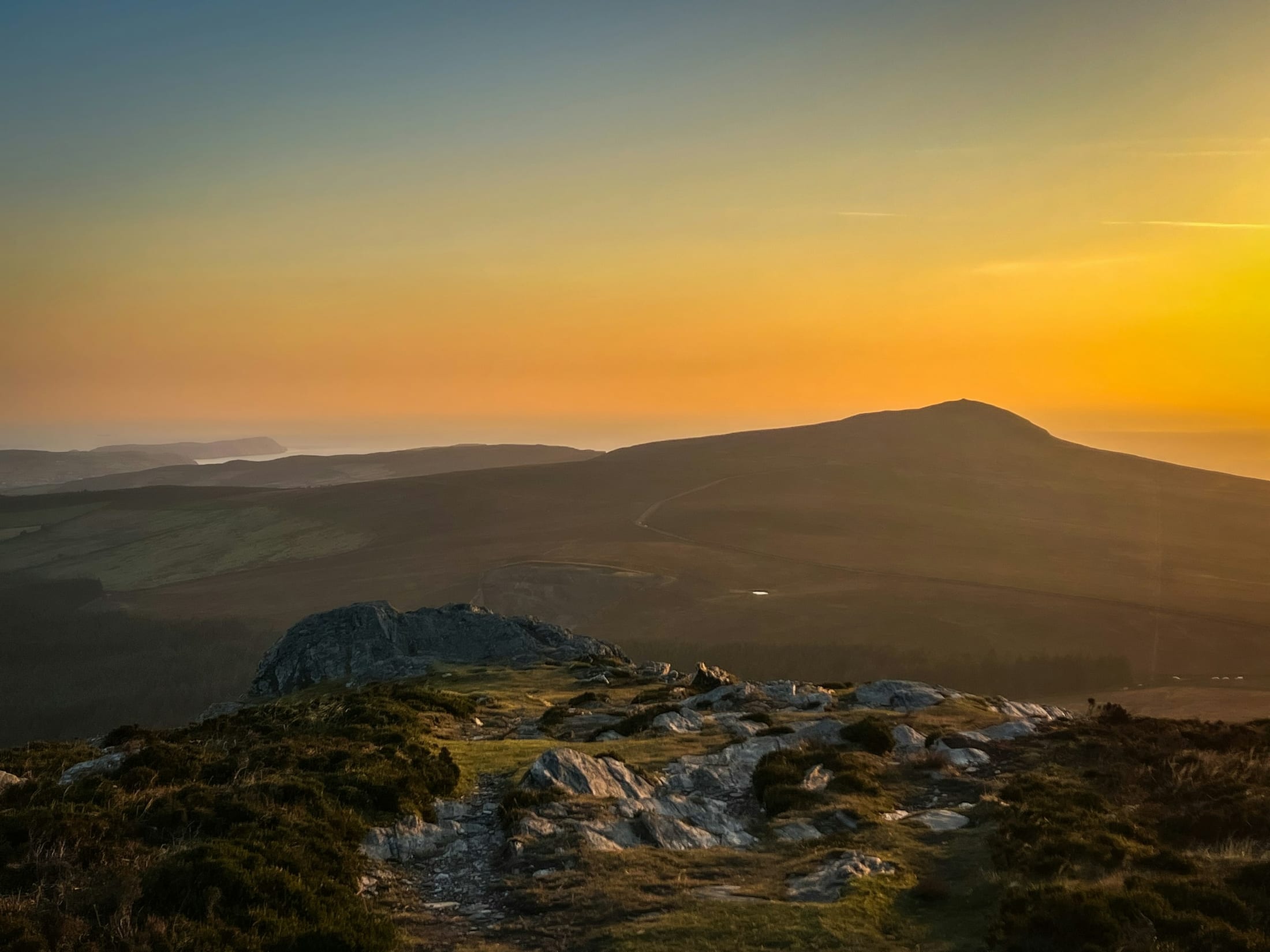 The sun setting over the hills of the Isle of Man, seen from a rocky summit